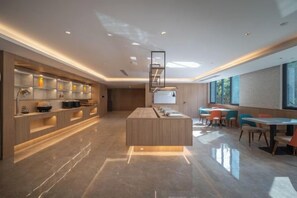 A modern kitchen with a central island, built-in shelves, and a dining area with chairs and tables. - HanTing Hotel (Xiamen Airport Wuyuan Bay) (Xiamen)