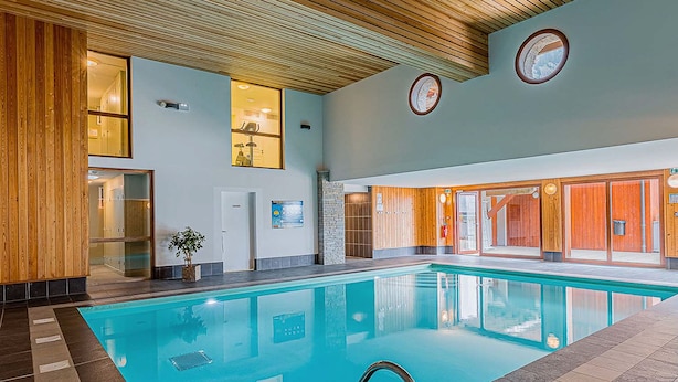 An indoor swimming pool with a wooden ceiling, glass walls, and a tiled floor. - La Cascade by Interhome (Vaujany)
