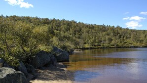 A natural landscape with a sandy beach, large rocks, and a forested area in the background. - Thorabu by Interhome (Eikerapen)