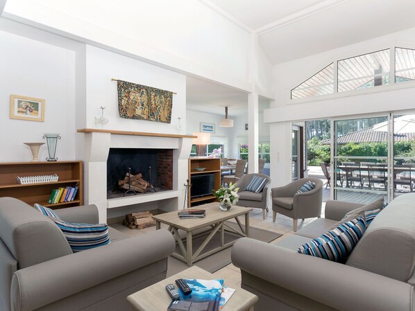 A spacious living room with a fireplace, comfortable seating, and a balcony with outdoor furniture.