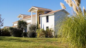 A two-story house with a tiled roof, a central porch, and a well-maintained lawn. - Club Royal Aquitaine by Interhome (Moliets)