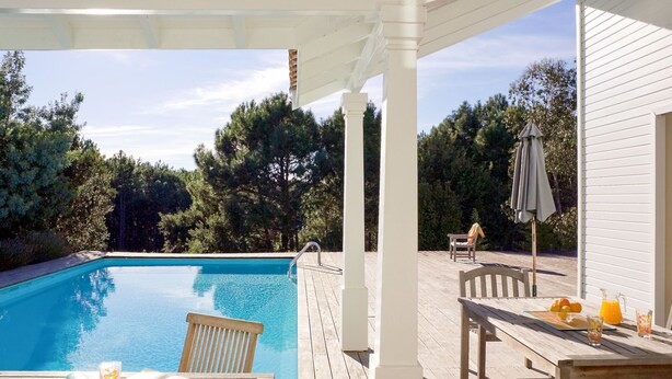 A wooden deck with a pool, outdoor furniture, and a pergola structure. - Club Royal Aquitaine by Interhome (Moliets)