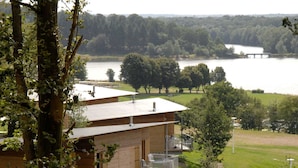 Eine Holzhütte mit Balkon, mit Blick auf einen See, umgeben von Bäumen.