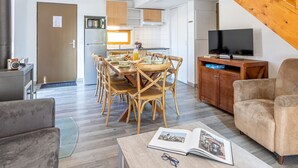 Ein modernes Wohnzimmer mit Essbereich, Küche und einer Treppe.