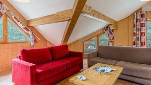 A cozy room with a red sofa, a brown sofa, and a wooden table with papers. - La Cascade by Interhome (Vaujany)
