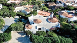 An aerial view of a coastal resort with villas featuring terracotta roofs, a beach, and clear blue waters. - Hibiscus by Interhome (Palau)