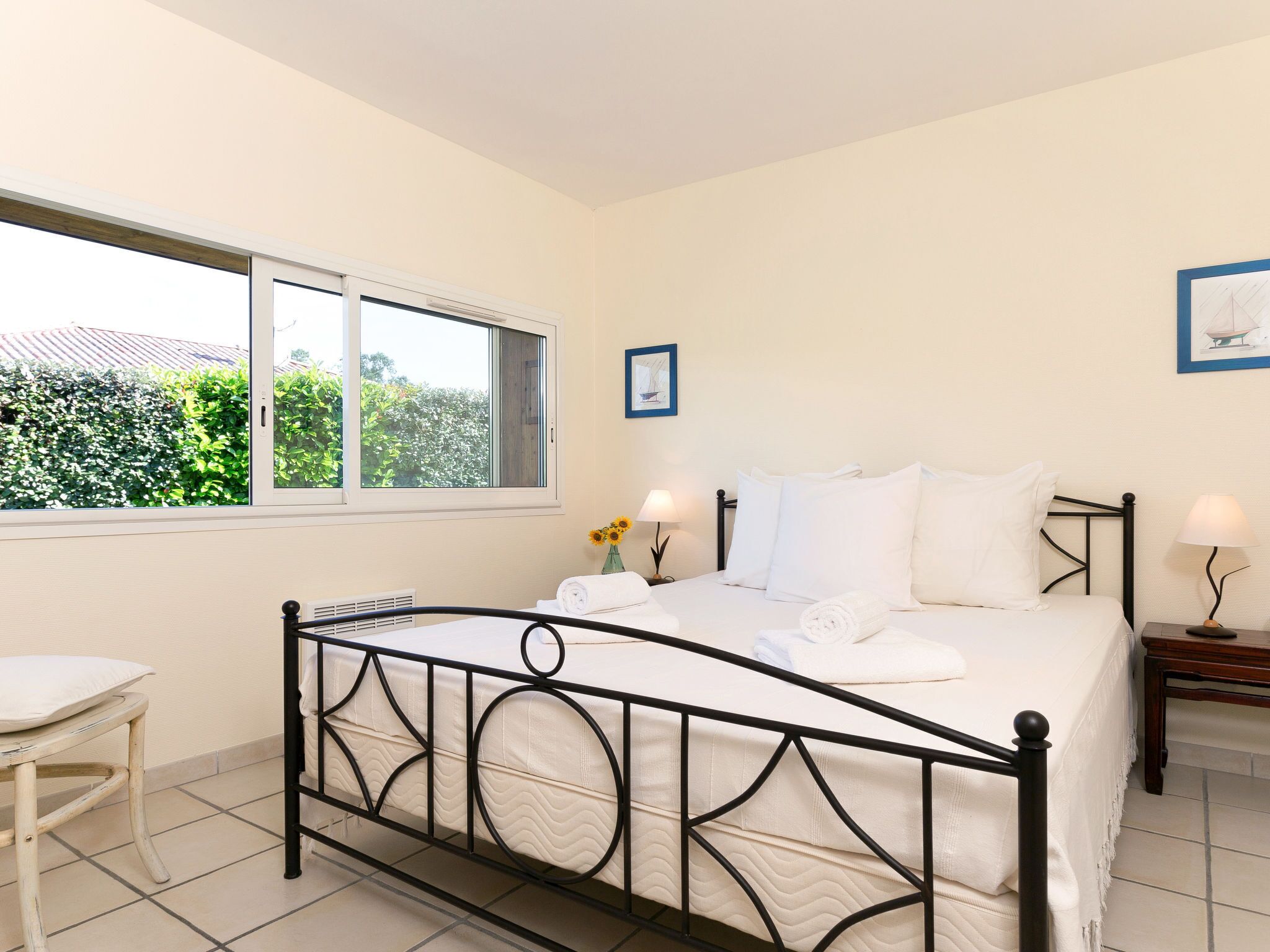 A bedroom with a bed, a window, a bedside table, and a chair.