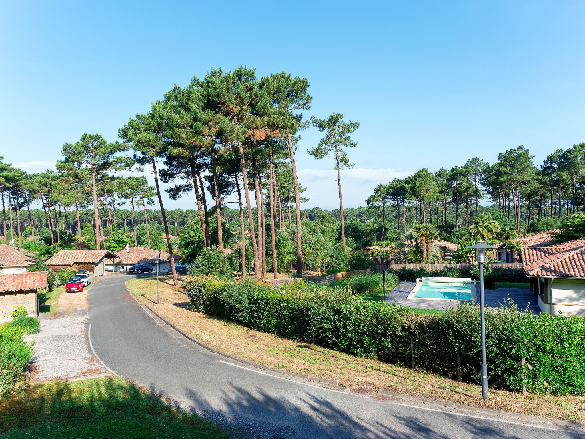 A residential area with a curved road, houses with tiled roofs, and a swimming pool.