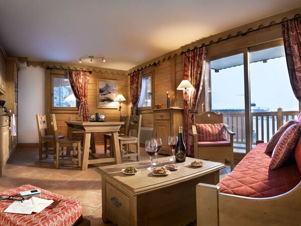 Una habitación acogedora con una mesa de comedor de madera, sillas, un sofá y un balcón con vistas.
