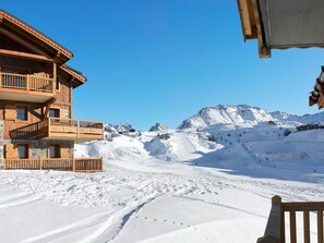 A wooden building with balconies overlooking a snowy mountain landscape.