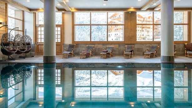 A spacious indoor pool area with clear views of a snowy mountain landscape through large windows. - Le Lodge des Neiges 5* by Interhome (Tignes)
