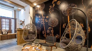 A modern interior with hanging chairs, a wooden coffee table, and a wall mural. - Le Lodge des Neiges 5* by Interhome (Tignes)