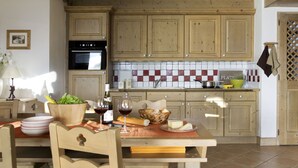 Cucina con mobili in legno, zoccolo paraschizzi in ceramica e zona pranzo con tavolo apparecchiato per due.