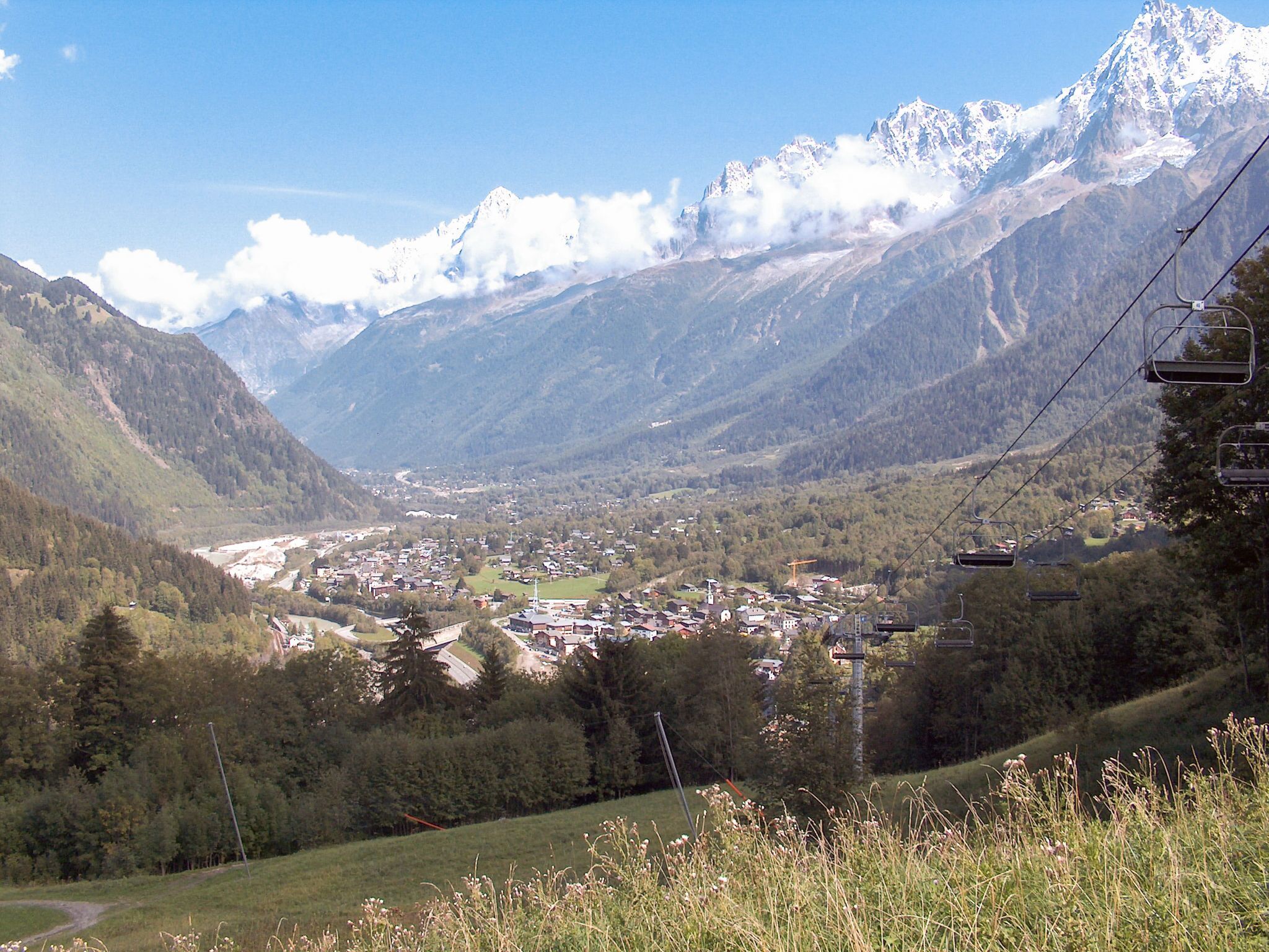 Eine Berglandschaft mit einem Talort, Skipisten und blauem Himmel.