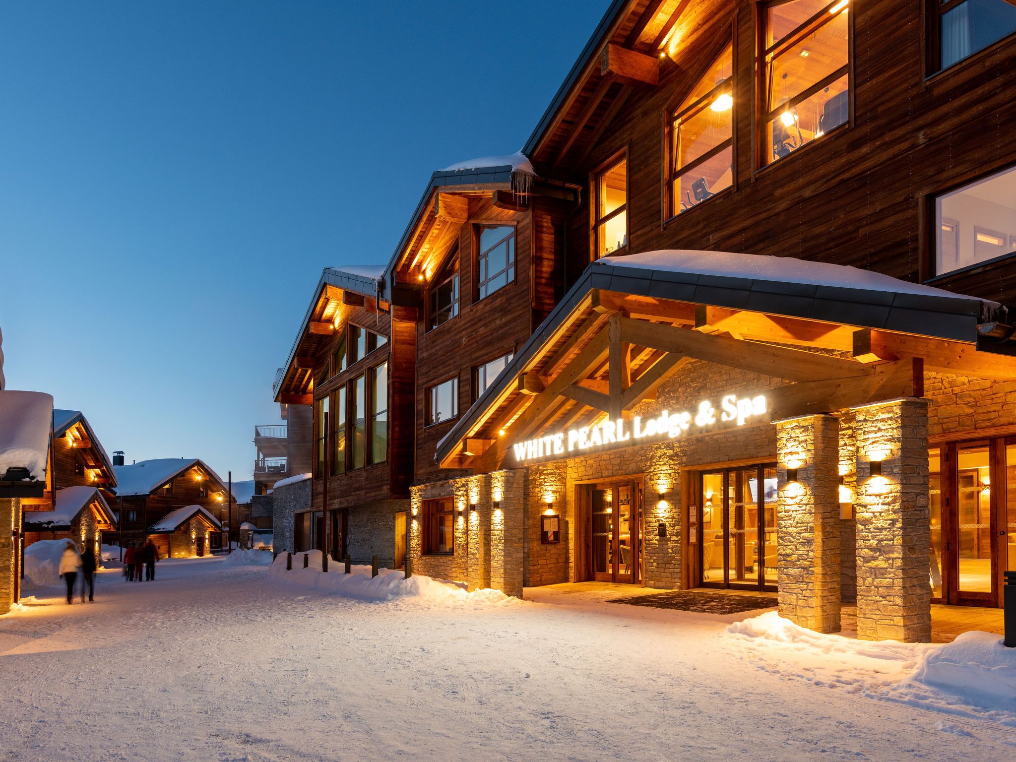 A snow-covered building with a sign reading "WHITE PEARL Lodge & Spa".