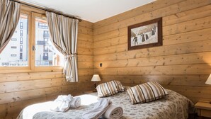 Una habitación acogedora de madera con una cama, un cuadro enmarcado en la pared y una ventana con cortinas.