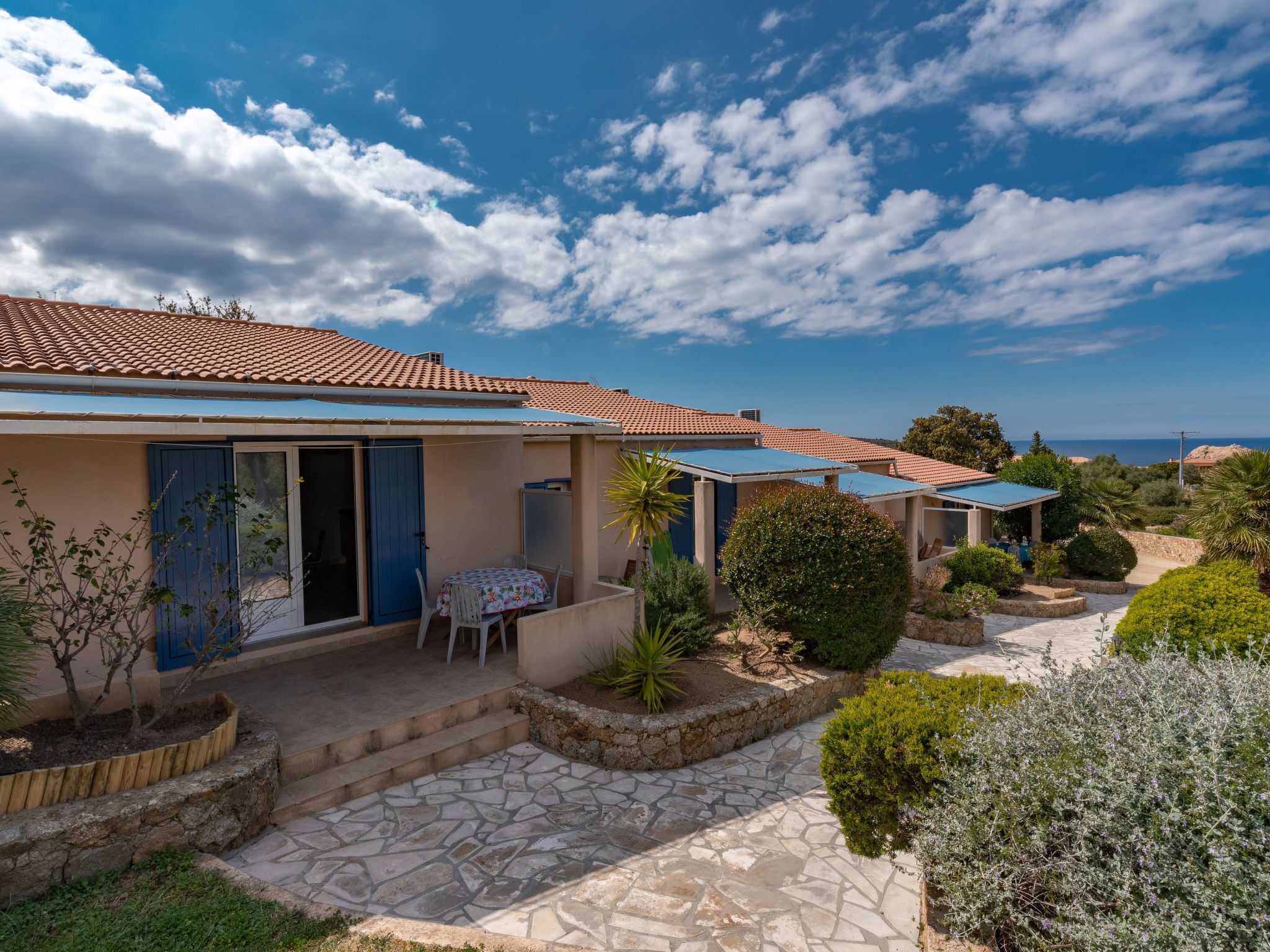 Ein Küsteneigentum mit terrakottafarbenen Dächern, einem gepflasterten Innenhof und Blick auf das Meer.