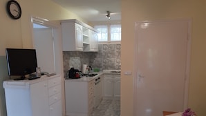 A compact kitchen with white cabinets, a gas stove, and a small dining table with a vase of flowers.