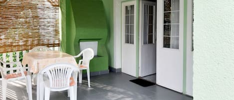 A patio area with a table and chairs, a green wall, and a door leading to another room.