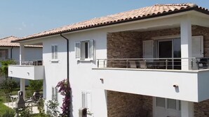 A two-story building with a balcony, outdoor seating, and a stone facade.