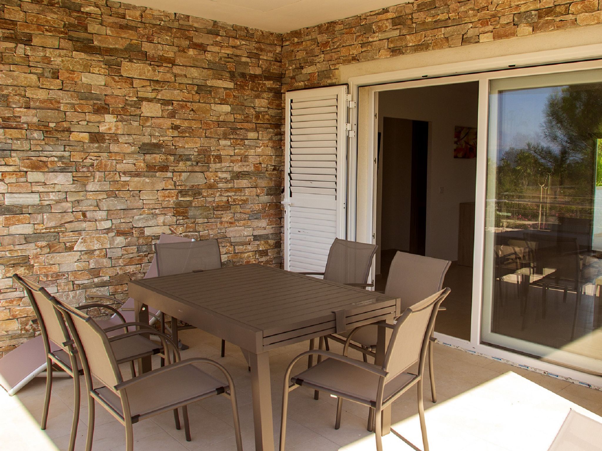A patio with a stone wall, a table, and chairs.