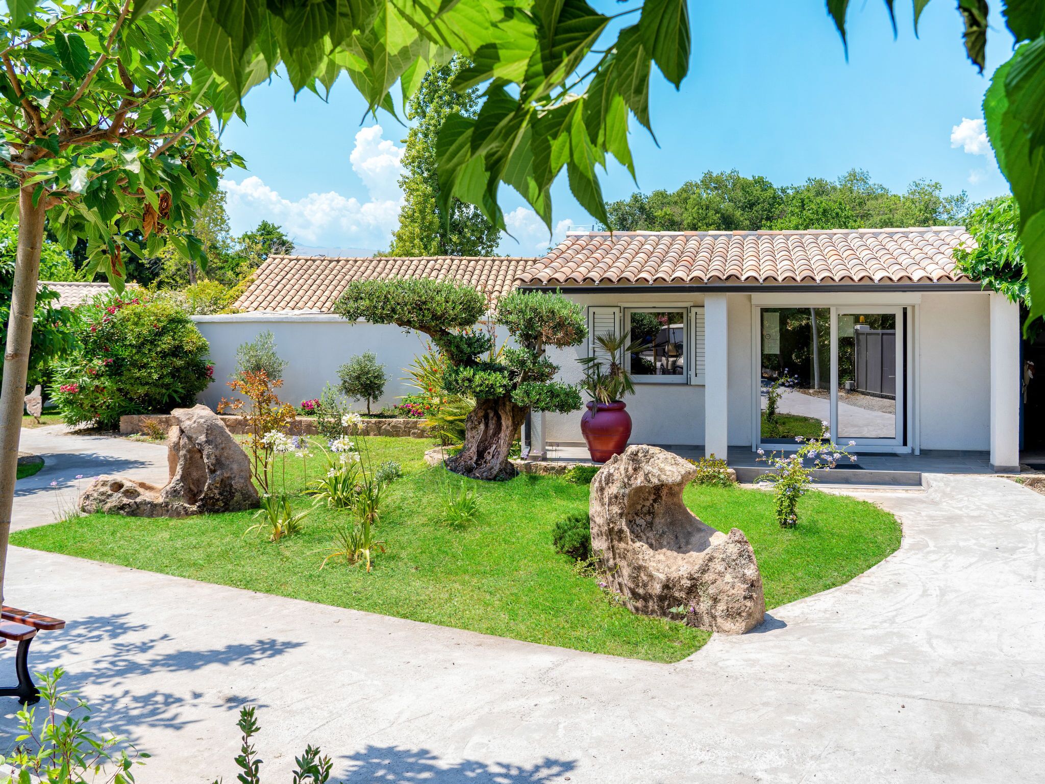 A modern house with a tiled roof, surrounded by a well-maintained garden with rocks and plants.