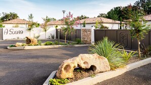 A parking lot with large rocks and plants, surrounded by buildings with a sign reading "A Suno". - A Suara by Interhome (Ghisonaccia)