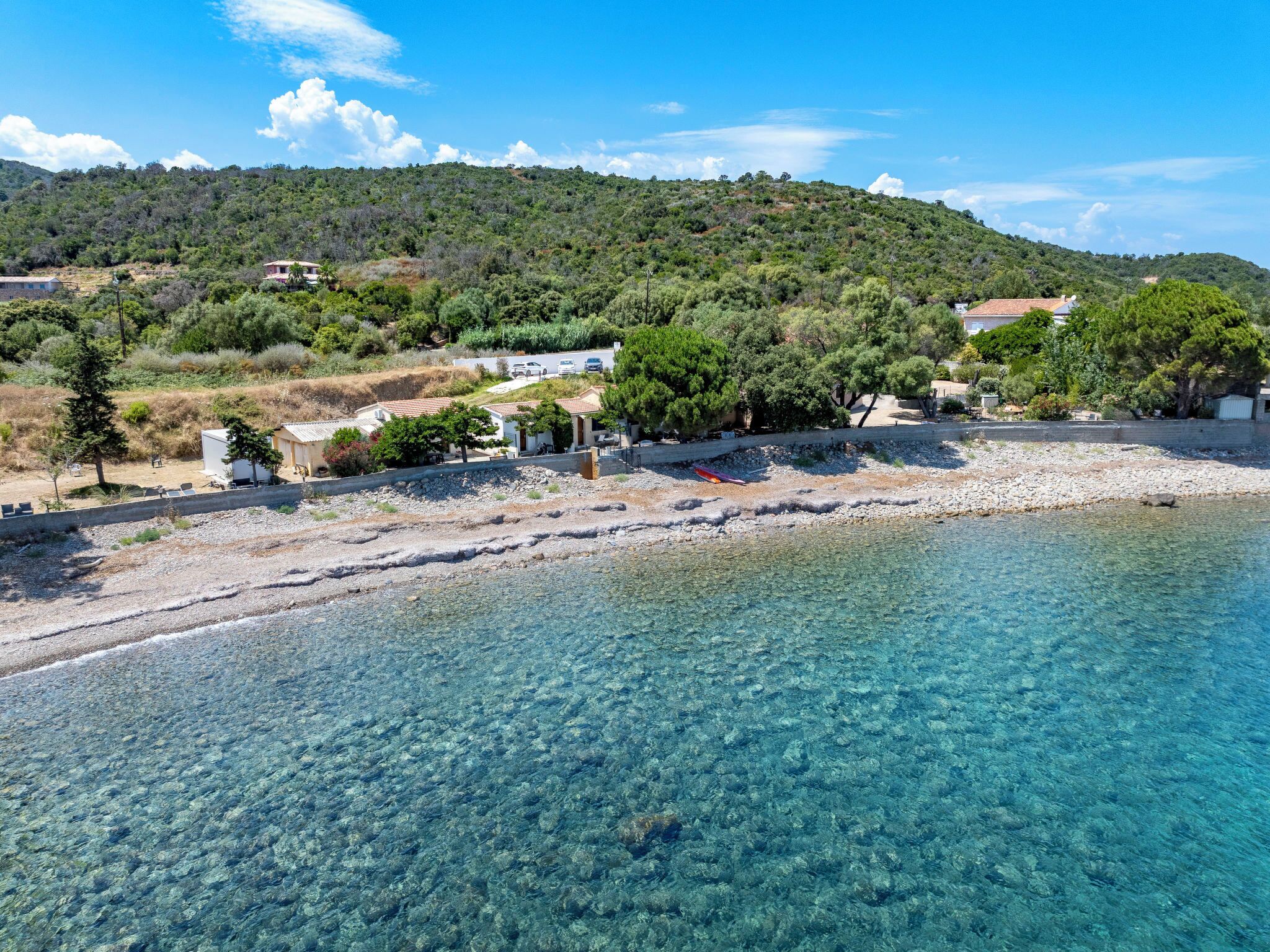 Eine Küstenlandschaft mit klarem Wasser, einem Strand und Gebäuden im Hintergrund.