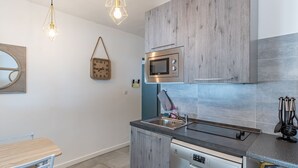 A modern kitchen with wooden cabinets, a built-in microwave, a dishwasher, and pendant lighting. - Vacation home Polpu by Interhome (Solenzara)