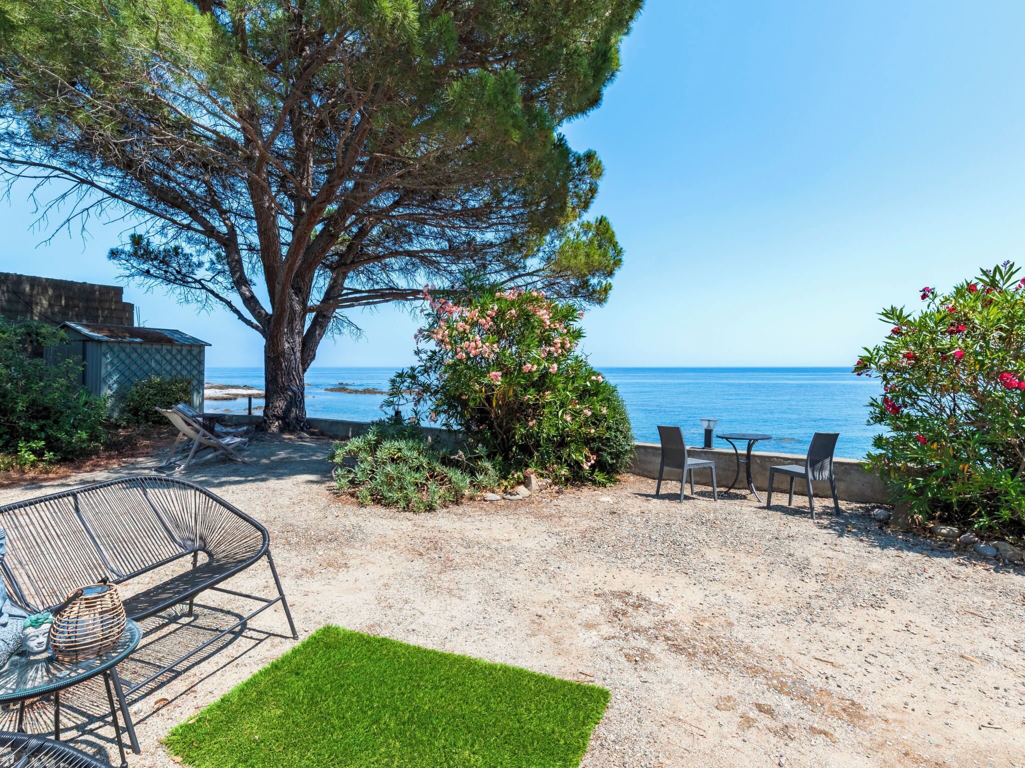 A patio with outdoor furniture, a tree, and a view of the sea.
