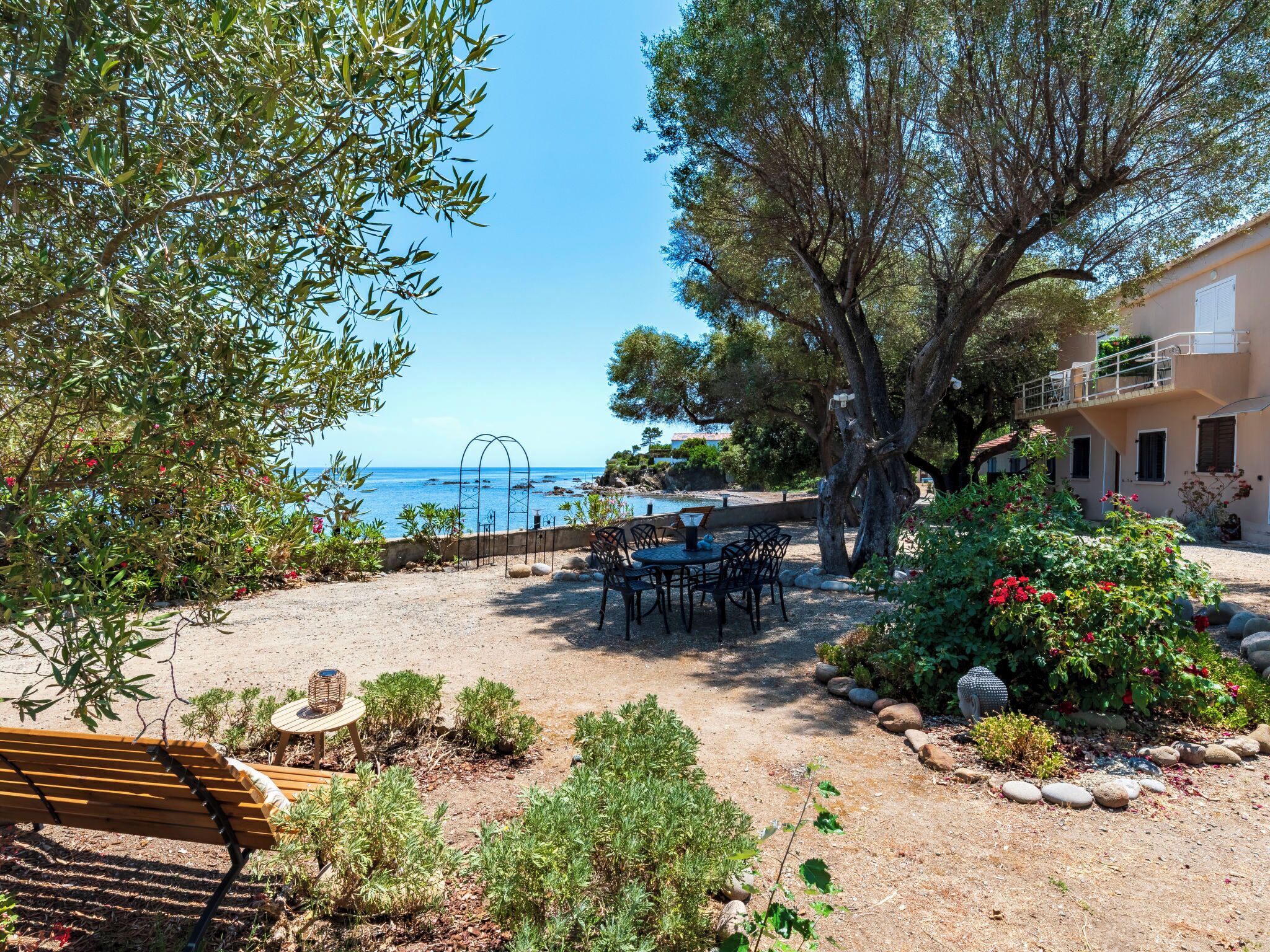 Une terrasse avec des meubles d’extérieur, une vue sur la mer et un bâtiment doté d’un balcon.
