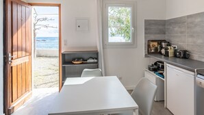 A modern kitchen with a view of the sea, a dining area, and a small seating space. - Mustella by Interhome (Solenzara)