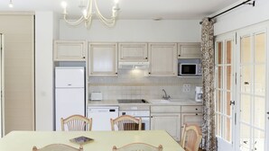 A kitchen with white cabinets, a microwave, a sink, and a dining table with chairs. - Domaine de Fayence M24 by Interhome (Fayence)