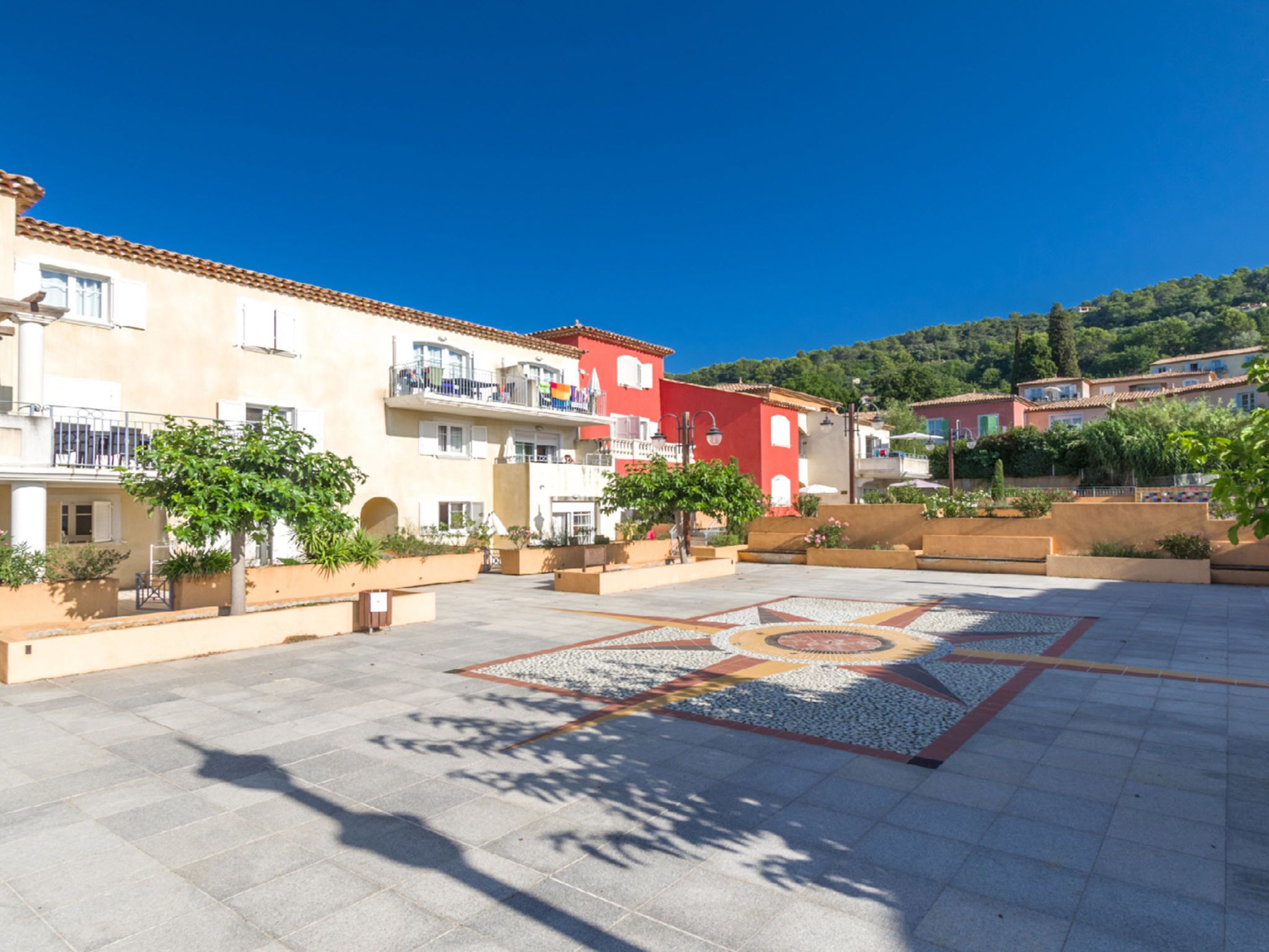 A courtyard with tiled flooring, surrounded by buildings with balconies and windows.