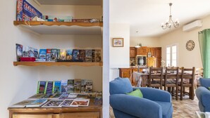 A living room with a blue sofa, wooden shelves with books, a dining area with a table and chairs, and a kitchen in the background. - Mas de la Gourmette by Interhome (Châteaurenard)