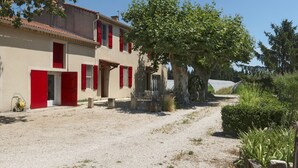 A building with red shutters, a gravel driveway, and a large tree in the foreground. - Mas de la Gourmette by Interhome (Châteaurenard)