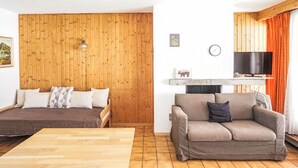 Une pièce chaleureuse avec un mur en bois, un lit, un canapé, une télévision et une cheminée.
