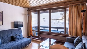 A cozy living room with a blue sofa, a glass coffee table, and a wooden ceiling. - Dixence 109 by Interhome (Thyon-Les Collons)