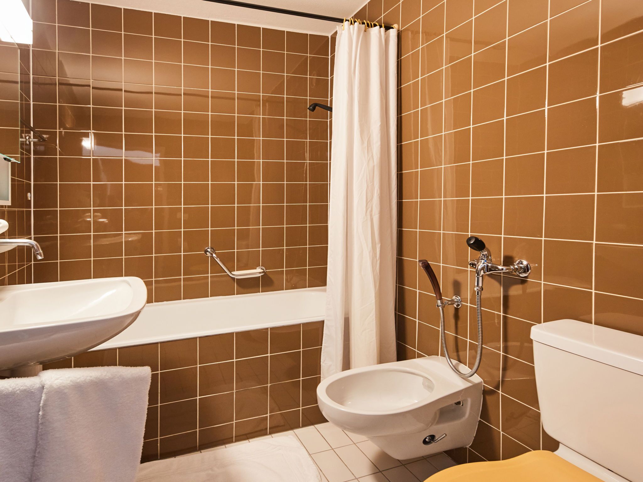 A bathroom with a bathtub, a toilet, and a bidet.