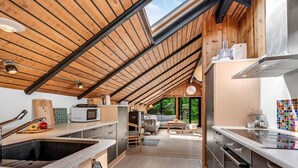 Een moderne keuken met dakraam, houten plafond en uitzicht op de omgeving.