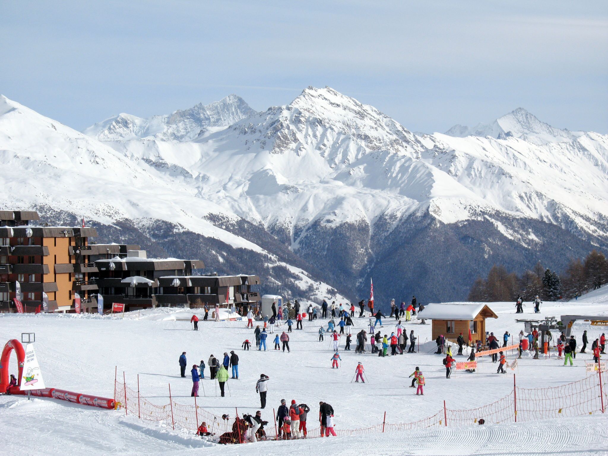 A ski resort with a ski slope, buildings, and mountains in the background.