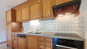 A kitchen with wooden cabinets, a stainless steel sink, a built-in oven, and a dishwasher. - Sérandes 18 by Interhome (Thyon-Les Collons)