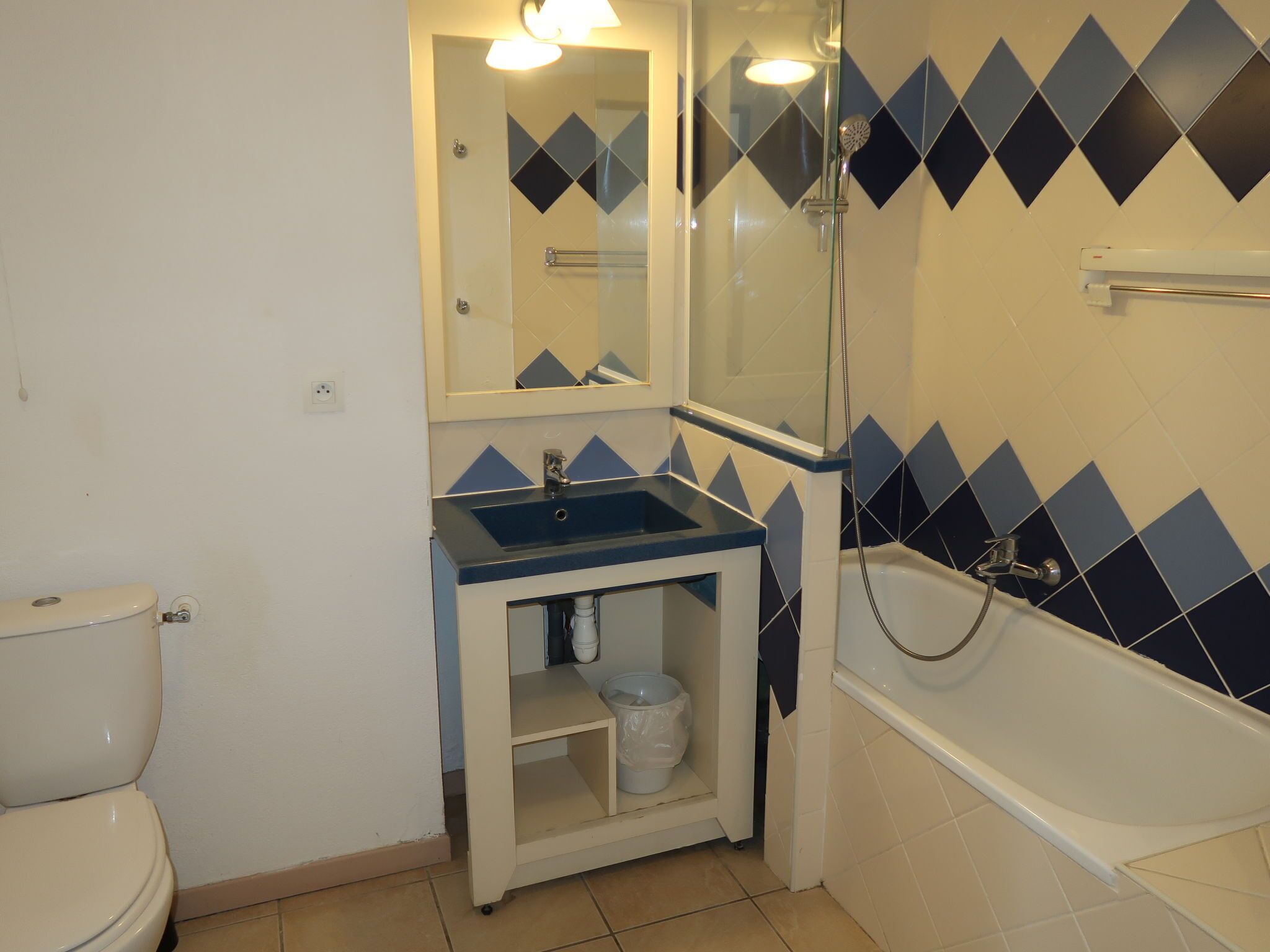 A bathroom with a toilet, sink, mirror, and shower.