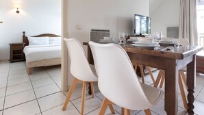 A hotel room with a bed, a dining table set for two, a TV, and a window with curtains. - Odalys Référence Le Domaine des Rois by Interhome (Bergheim)