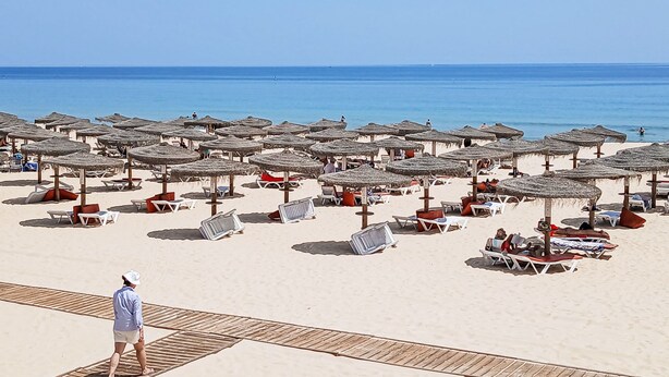Een strand met veel parasols en ligbedden.