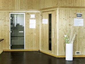 A wooden interior with a staircase, a white vase with plants, and informational signs.
