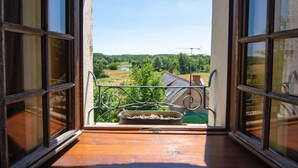 A balcony with a view of a rural landscape, including fields and a body of water.