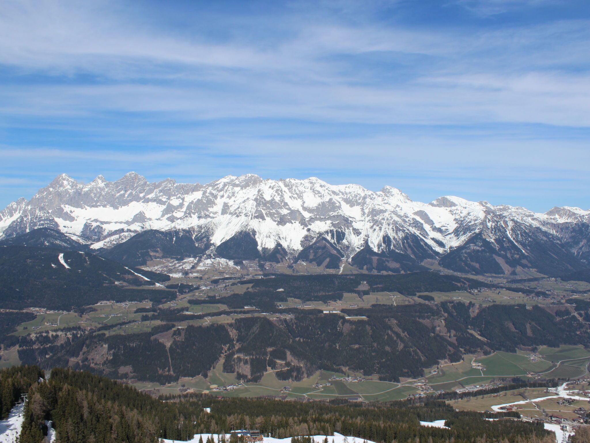 A mountain range with snow-capped peaks and a valley below.
