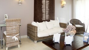 Una sala de estar con un sofá de mimbre, un sillón a juego, una mesita de centro y dos lámparas de pared.