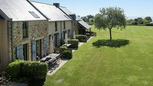 A row of stone buildings with a well-maintained lawn and a tree.
